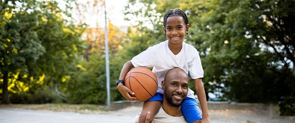 Dad and son playing basketball, son on top of dad's shoulders